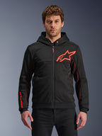 Alpinestars Chrome Air Sport Hoodie, czarna bluza z kapturem na zamek z czerwonym fluorescencyjnym logo gwiazdy i akcentami na rękawach, czerwone panele boczne z siateczki dla wentylacji, miejska odzież motocyklowa casualowa noszona przez modela