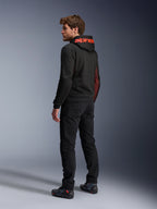 Alpinestars Chrome Air Sport Hoodie, miejska bluza motocyklowa, czarna i czerwona Fluo, widok z tyłu przedstawiający czerwone logo Alpinestars na kapturze i siatkowe panele boczne, noszona z czarnymi spodniami motocyklowymi i obuwiem technicznym