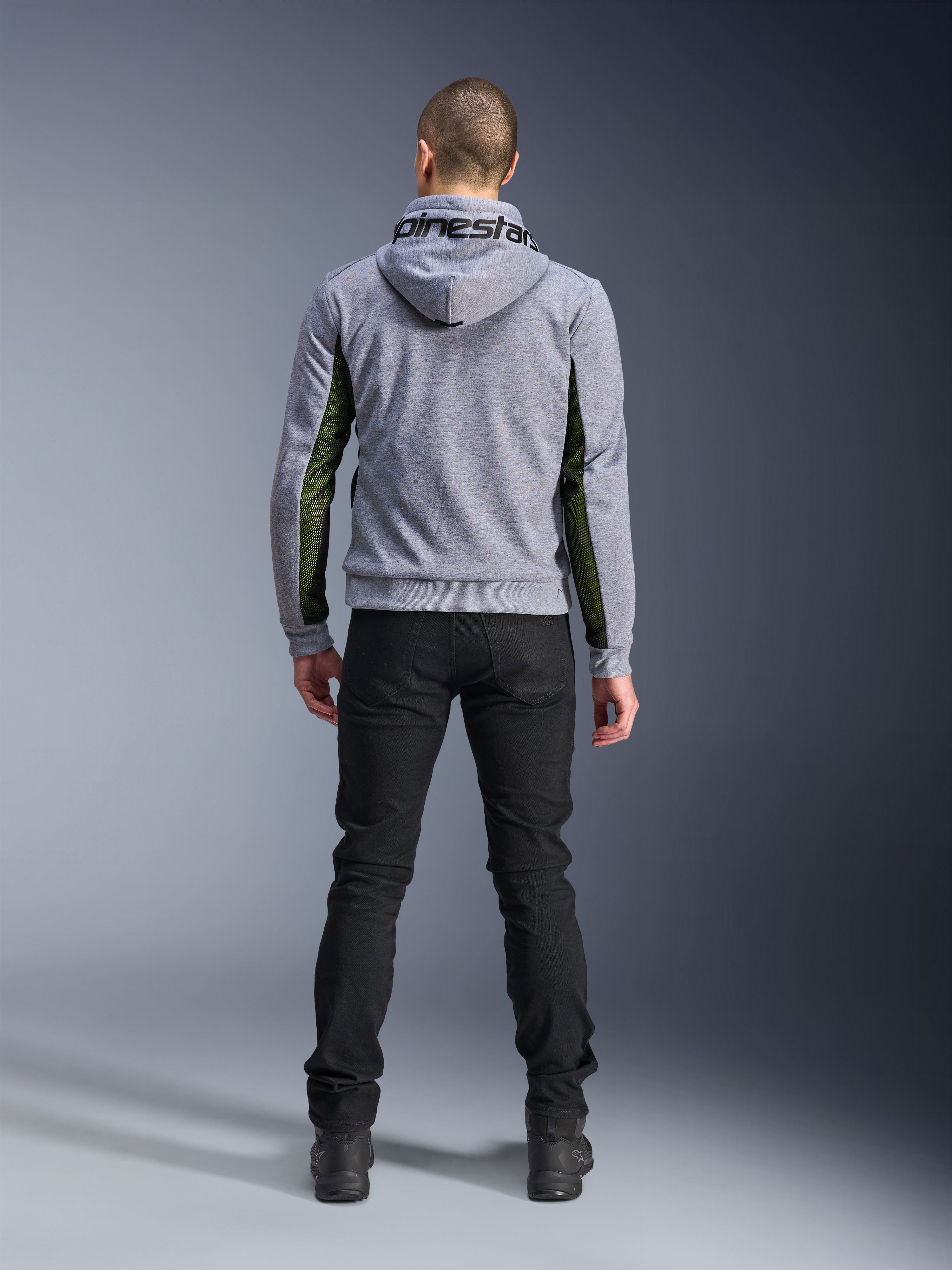 Alpinestars Chrome Air Sport Hoodie, Gray Heather Black, widok od tyłu motocyklowej bluzy z kapturem z zielonymi panelami z siatki o wysokim przepływie powietrza na bokach i rękawach, konstrukcja z technicznego polaru z logo Alpinestars na kapturze, zestawiona z czarnymi spodniami