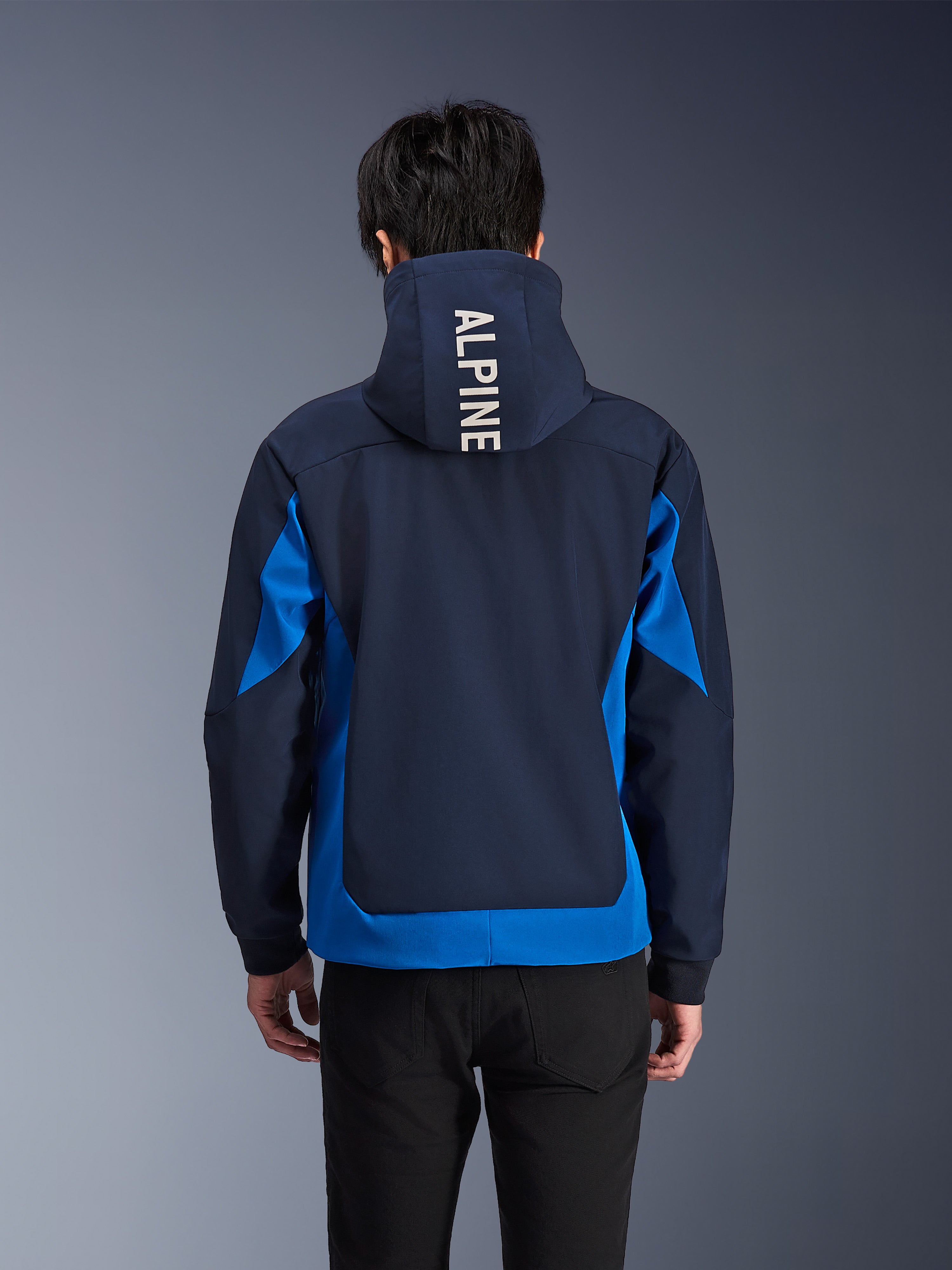 Alpinestars Radium Tech Hoodie, kurtka motocyklowa w kolorach Night Navy i Royal Blue, widok z tyłu prezentujący biały napis „ALPINE” na kapturze, miejska odzież techniczna o sportowym kroju z kontrastującymi panelami kolorystycznymi