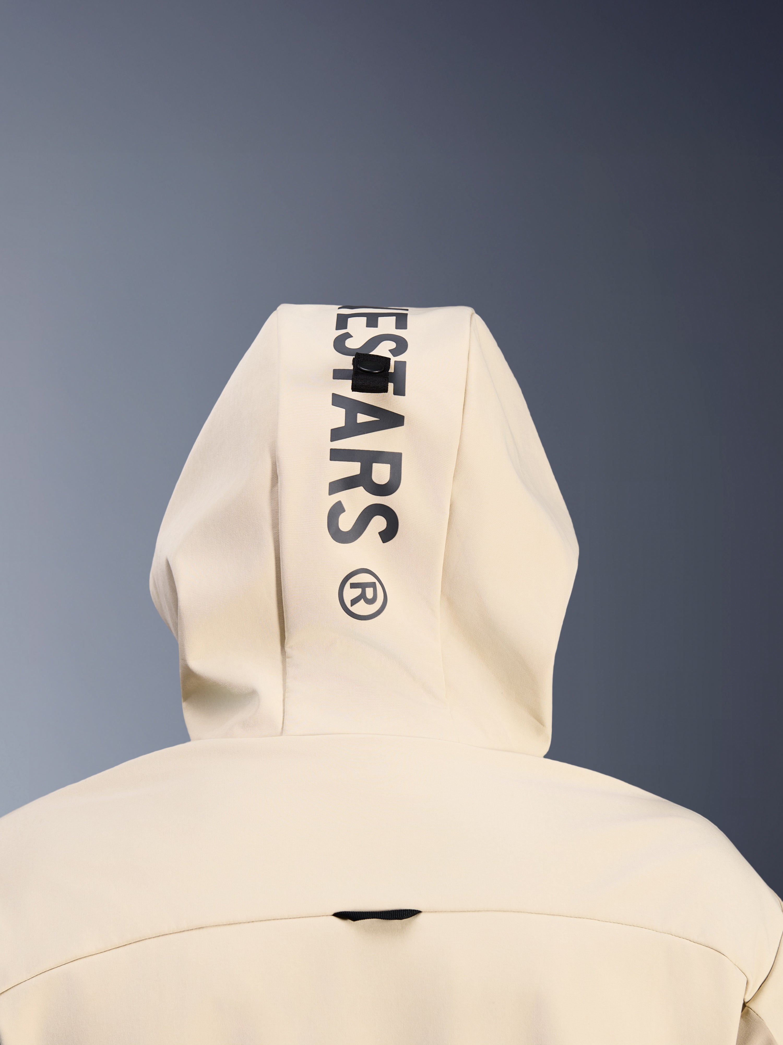 Bluza Alpinestars Radium Tech Hoodie w kolorze Mastic Aluminum, zbliżenie na tył kaptura, pionowe czarne logo Alpinestars, system pętli do mocowania kaptura, detal miejskiej odzieży motocyklowej