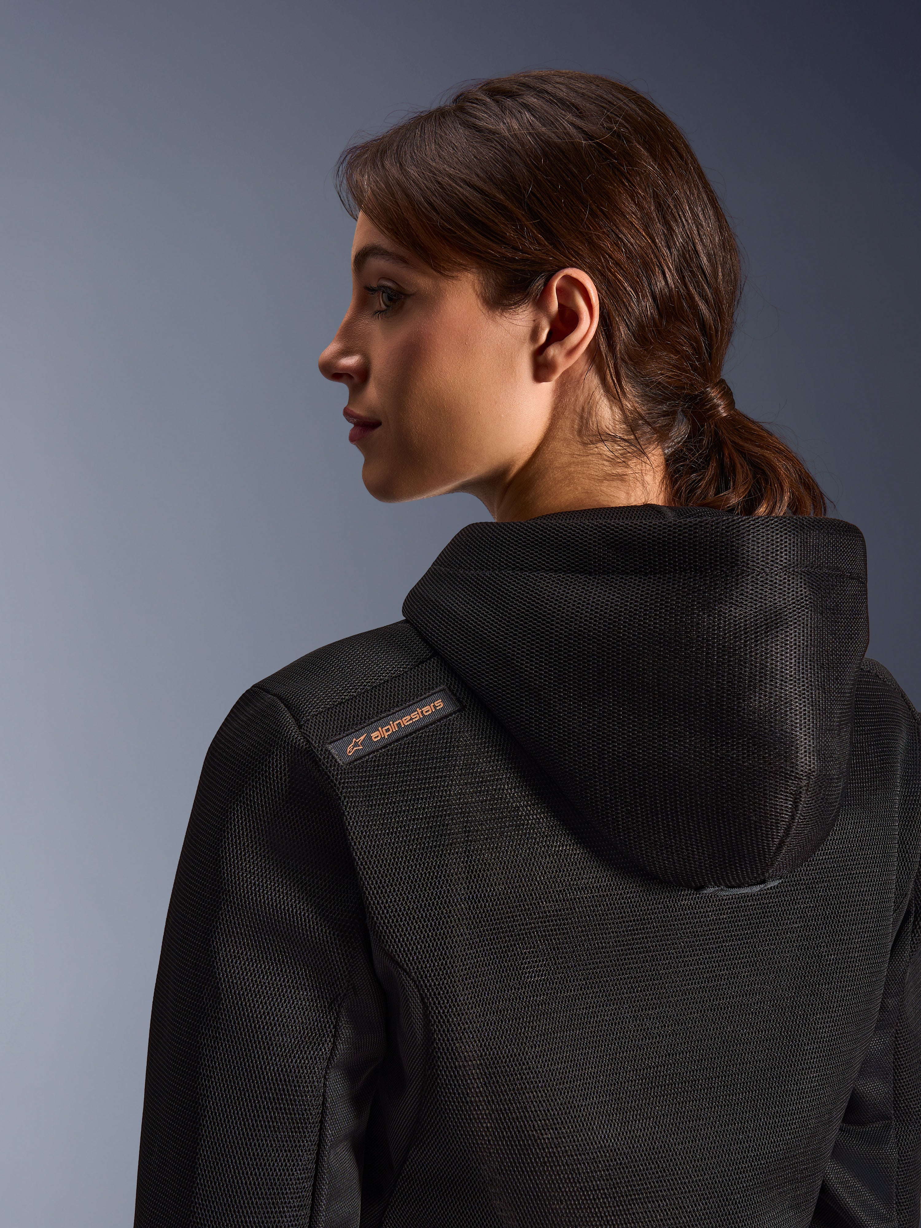 Alpinestars Stella Chrome Superairflow Hoodie, damska bluza motocyklowa, czarna z miedzianym detalem logo, zbliżenie na konstrukcję z siatki 3D na plecach i ramieniu, techniczna odzież ochronna do sportowej jazdy miejskiej