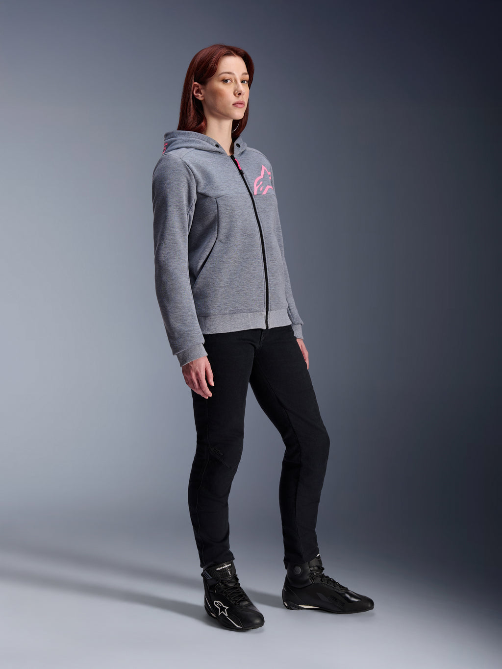 Alpinestars Stella Chrome V2 Sport Hoodie, damska bluza motocyklowa, szary melanż i różowy fluo, zestawiona z czarnymi spodniami do jazdy i czarnymi butami, miejska odzież motocyklowa w swobodnym stylu