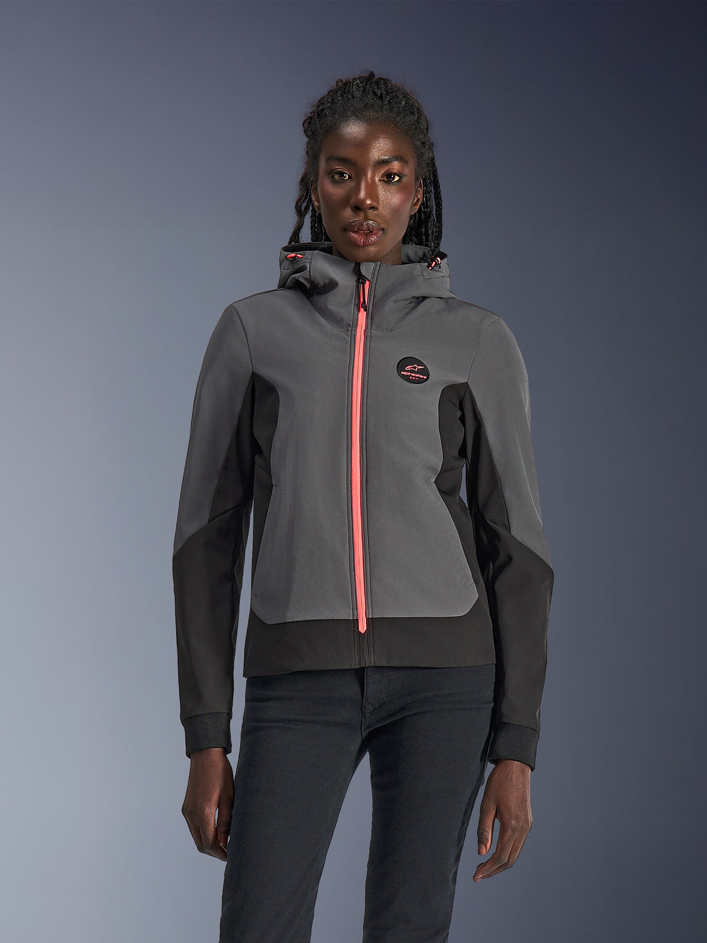 Alpinestars Stella Radium Tech Hoodie, damska bluza motocyklowa z kapturem, ciemnoszara i czarna z jaskraworóżowym zamkiem i sznurkami przy kapturze, prezentowana na modelce, sportowy miejski design z logo Alpinestars na piersi