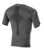 Alpinestars Roost Base Layer Top, techniczna warstwa bazowa do motocrossu, kolor antracytowo-czarny, widok z tyłu przedstawiający dzianinową, oddychającą konstrukcję, teksturowaną centralną strefę wentylacyjną, krótkie rękawy oraz logo gwiazdy Alpinestars na kołnierzu i rękawie