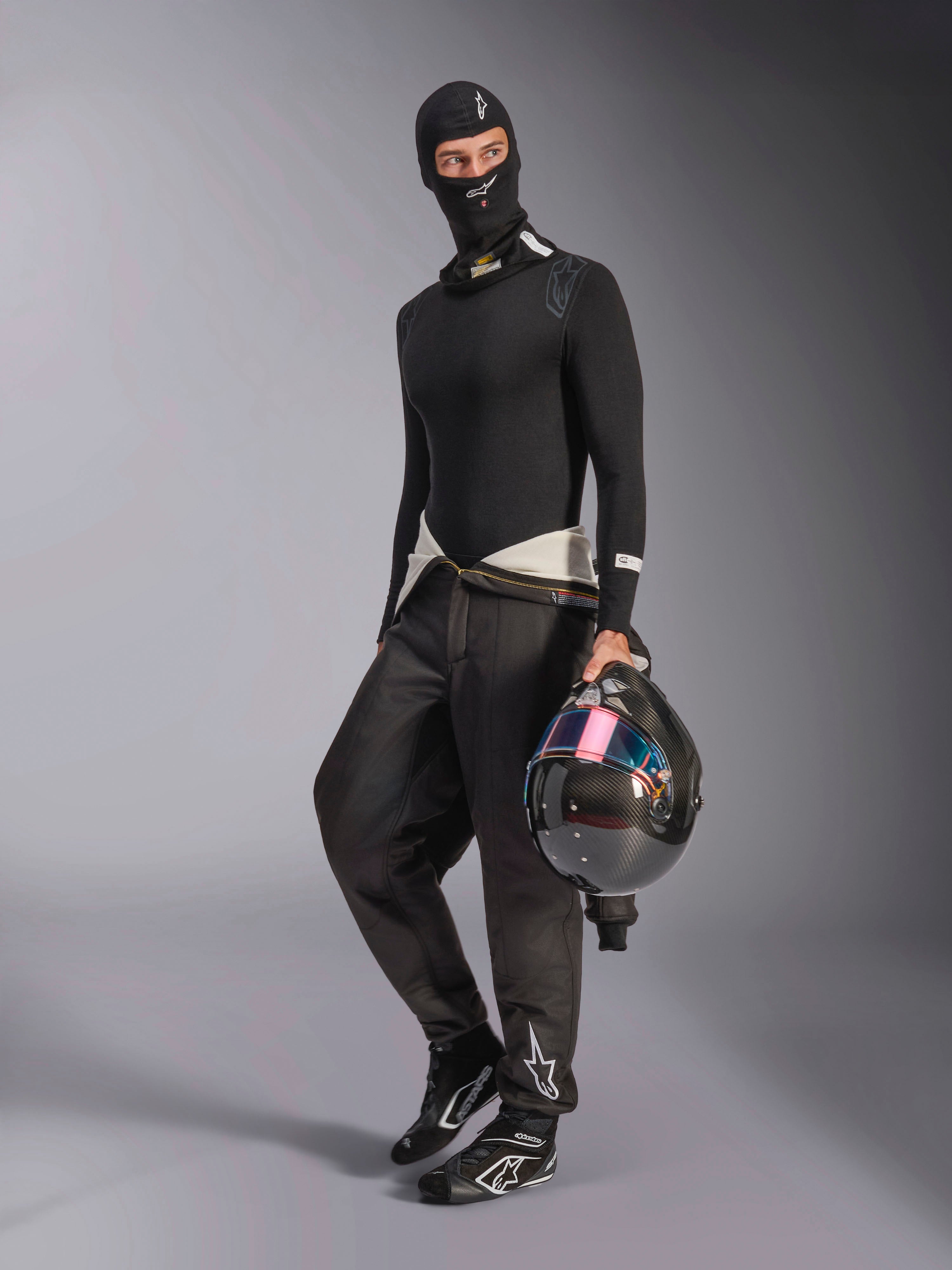 Alpinestars ZX Evo V3 Balaclava, czarna kominiarka noszona przez kierowcę w pełnym zestawie samochodowej bielizny termoaktywnej, białe logo na czole, kask z włókna węglowego z opalizującym wizjerem, profesjonalna ognioodporna odzież motorsportowa