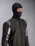Kominiarka Alpinestars ZX Evo V3, czarna, ognioodporna kominiarka wyścigowa, noszona przez modela w czarnym kombinezonie z białymi akcentami, logo Alpinestars na podbródku, otwór na rurkę nawadniającą, profesjonalny sprzęt ochronny do sportów motorowych