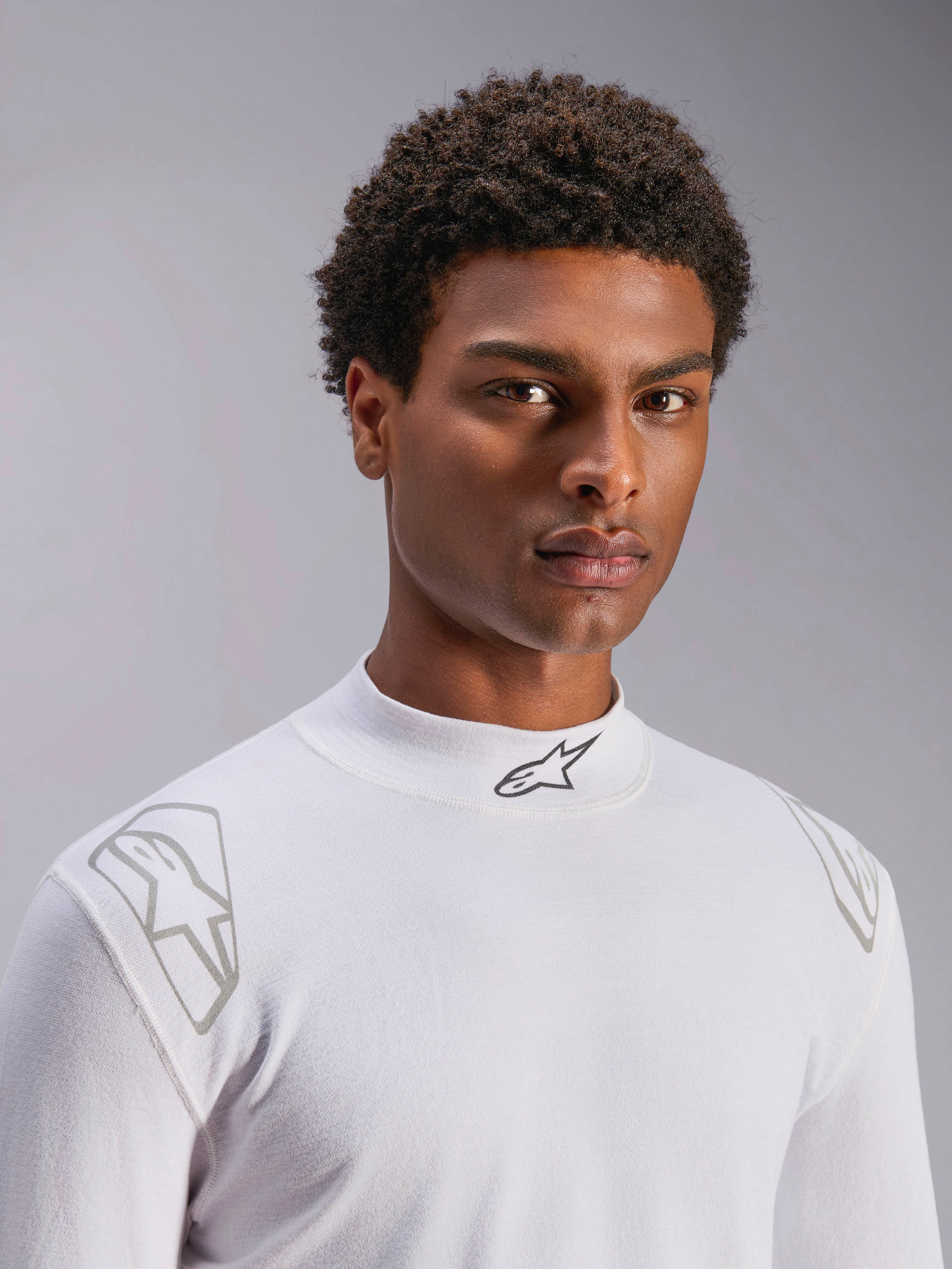 Alpinestars ZX Evo V3 Top - z długim rękawem, biała samochodowa bielizna rajdowa, prezentowana na modelu, stójka z czarnym logo Alpinestars, srebrne nadruki graficzne na ramionach, lekka i ognioodporna