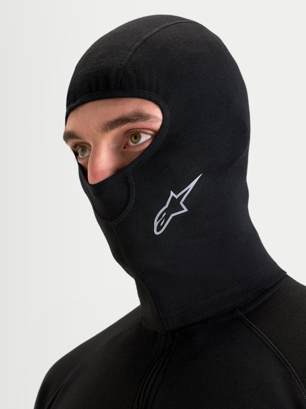 Alpinestars AT-8 Merino Balaclava, black all-terrain motorcycle balaclava worn by a model, showing dual-layer merino wool blend construction, extended neck coverage, and white Alpinestars logo branding on the side