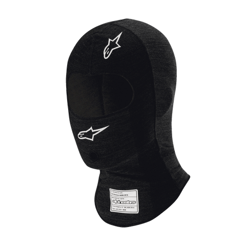 Alpinestars Race V3 Balaclava, czarna ognioodporna kominiarka wyścigowa, białe logo z gwiazdą na czole i policzku, etykieta z certyfikatem FIA na szyi, lekka tkanina techniczna z otworem na oczy, ochrona głowy w sportach motorowych