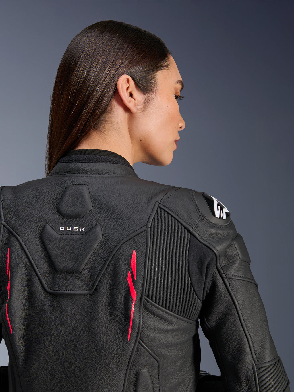 Alpinestars Stella Dusk Leather Jacket, damska kurtka skórzana, czarna z akcentami Diva Pink i białym logo na ramieniu, widok z tyłu pokazujący branding DUSK oraz harmonijkowe panele elastyczne, sportowy ergonomiczny design