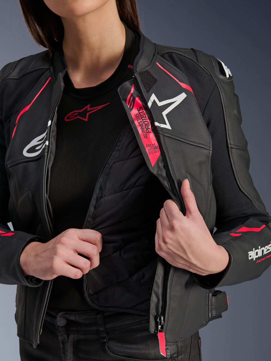 Damska skórzana kurtka Alpinestars Stella Dusk, czarna z różem Diva Pink i białym, skórzana kurtka motocyklowa rozpięta, aby pokazać wewnętrzną pikowaną podpinkę ocieplającą oraz branding Tech-Air Ready, białe logo i jaskrawe różowe akcenty.
