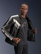 Alpinestars T-Dyno WR Jacket, czarna, ciemnoszara i ecru, tekstylna kurtka motocyklowa o kroju inspirowanym stylem vintage, detale w paski na klatce piersiowej i rękawach, noszona na czarnym t-shircie z grafiką, miejska odzież motocyklowa