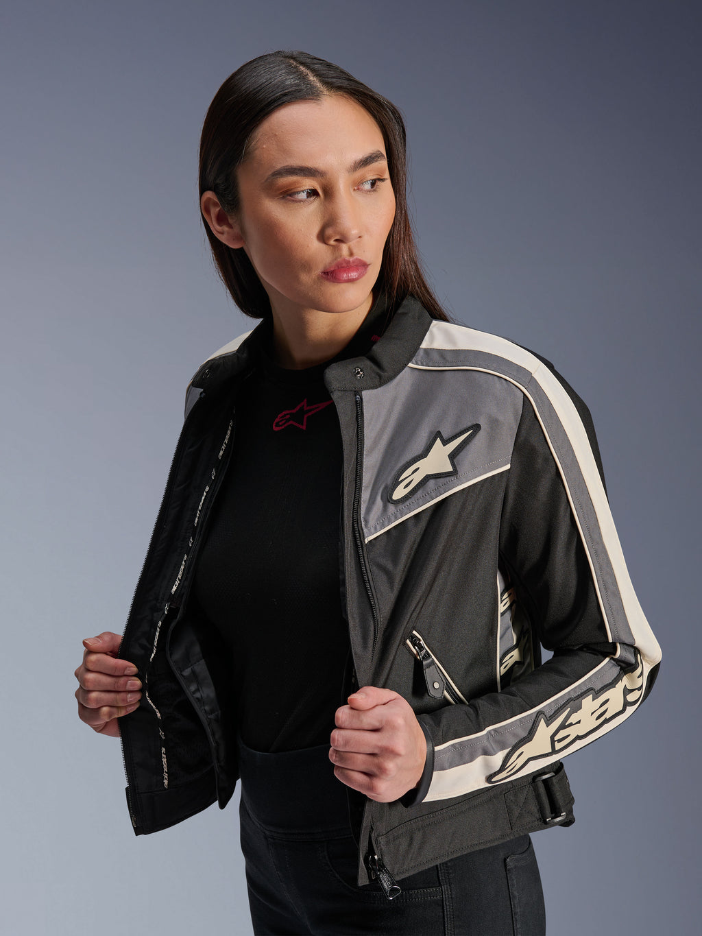 Damska kurtka Alpinestars Stella T-Dyno WR, tekstylna kurtka motocyklowa, czarna, ciemnoszara i ecru, design inspirowany stylem vintage ze sportowymi pasami i logo na piersi i rękawach, prezentowana przez modelkę, miejska odzież motocyklowa