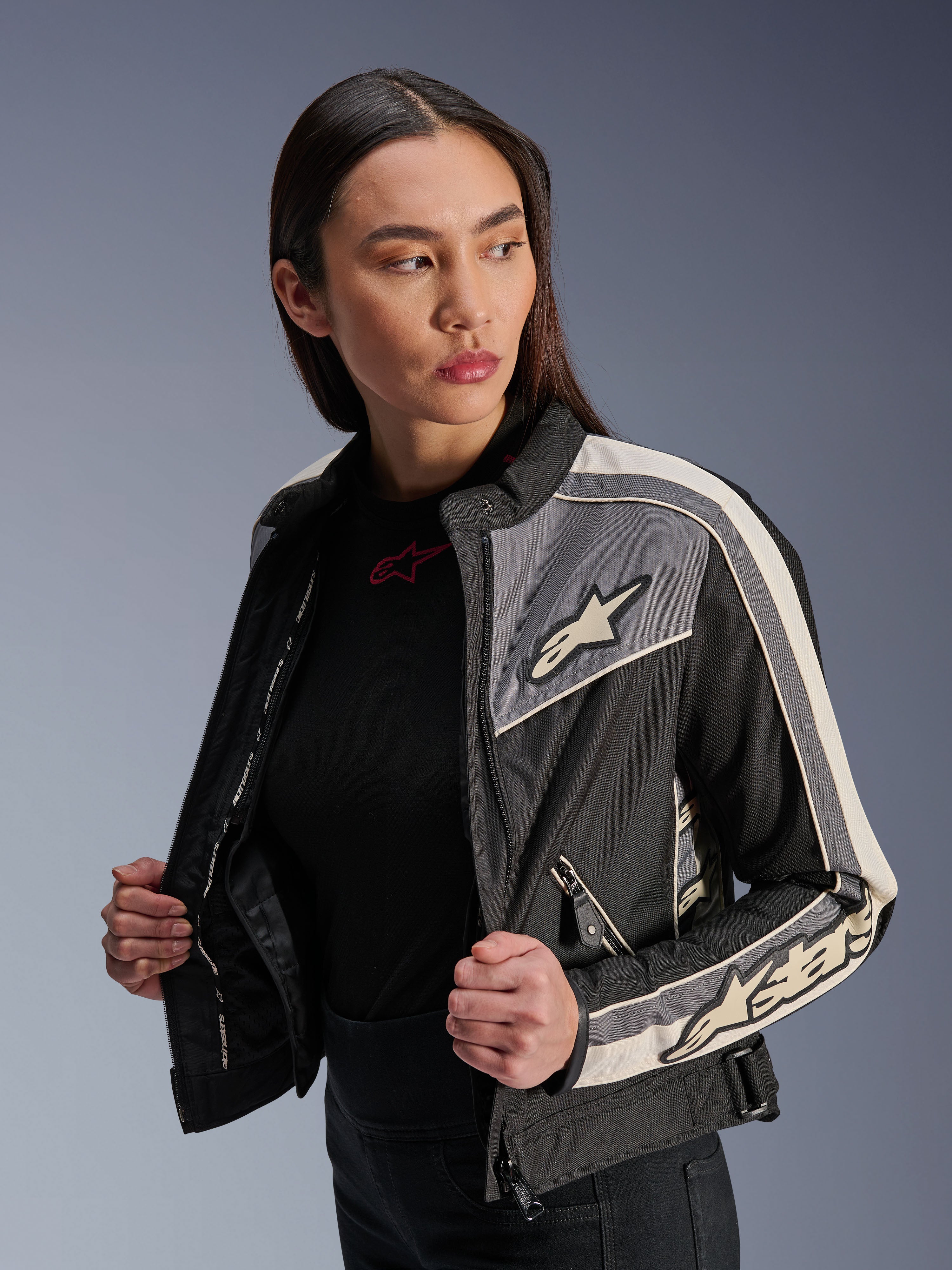 Damska kurtka Alpinestars Stella T-Dyno WR, tekstylna kurtka motocyklowa, czarna, ciemnoszara i ecru, design inspirowany stylem vintage ze sportowymi pasami i logo na piersi i rękawach, prezentowana przez modelkę, miejska odzież motocyklowa