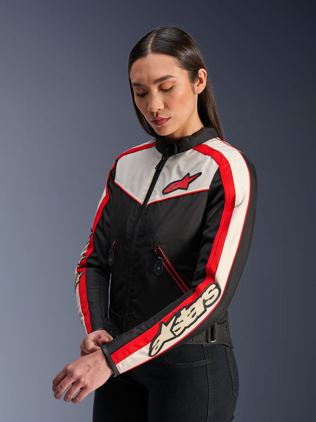 Alpinestars Stella T-Dyno WR Jacket, damska tekstylna kurtka motocyklowa, kolor czarny, ecru i jaskrawoczerwony, design inspirowany stylem vintage z czerwonym logo Alpinestars na piersi i oznaczeniem marki na rękawie, prezentowana przez modelkę w studio.