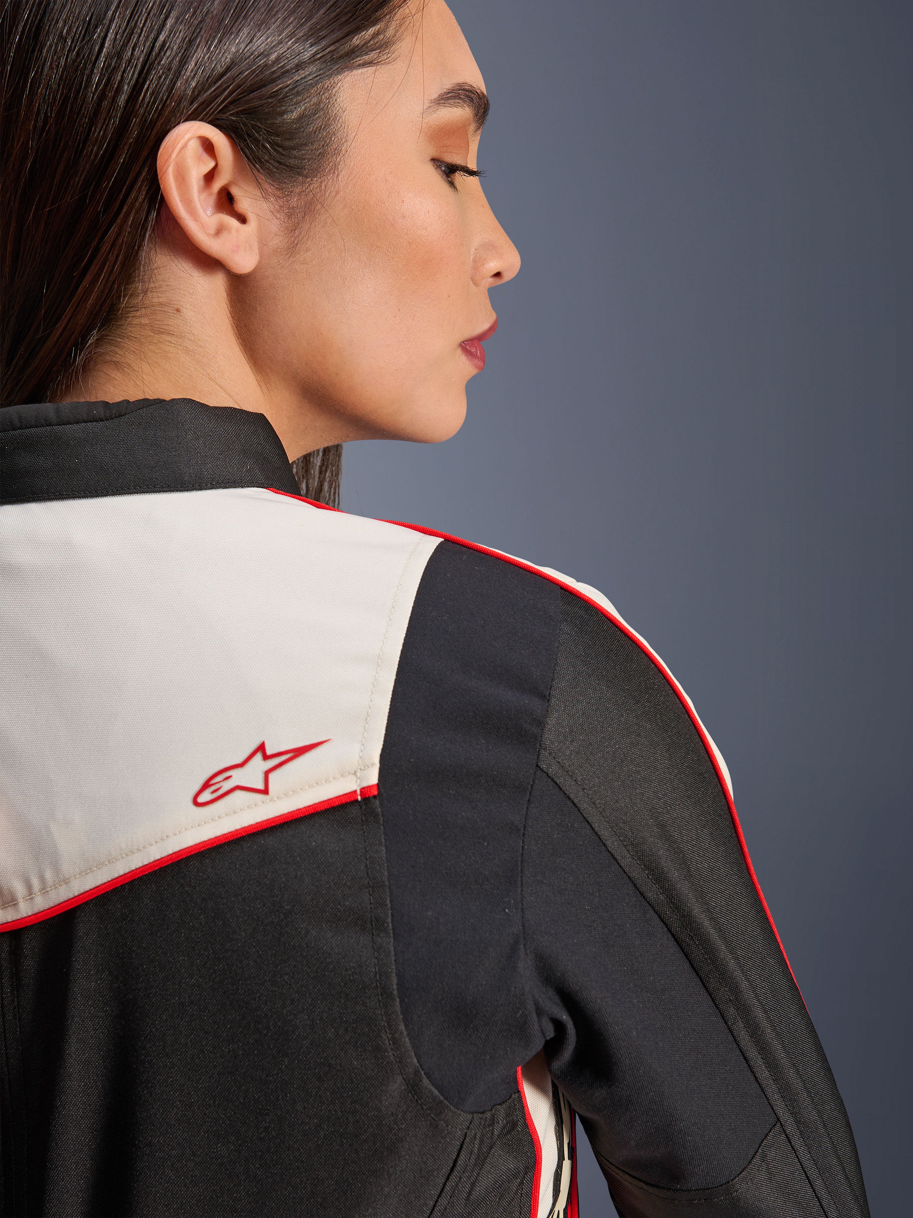 Kurtka Alpinestars Stella T-Dyno WR w kolorze Black Ecru Bright Red, zbliżenie na ramię i plecy, panele w kolorze ekri z czerwonymi lamówkami, czerwone logo z gwiazdą Alpinestars, damska tekstylna odzież motocyklowa