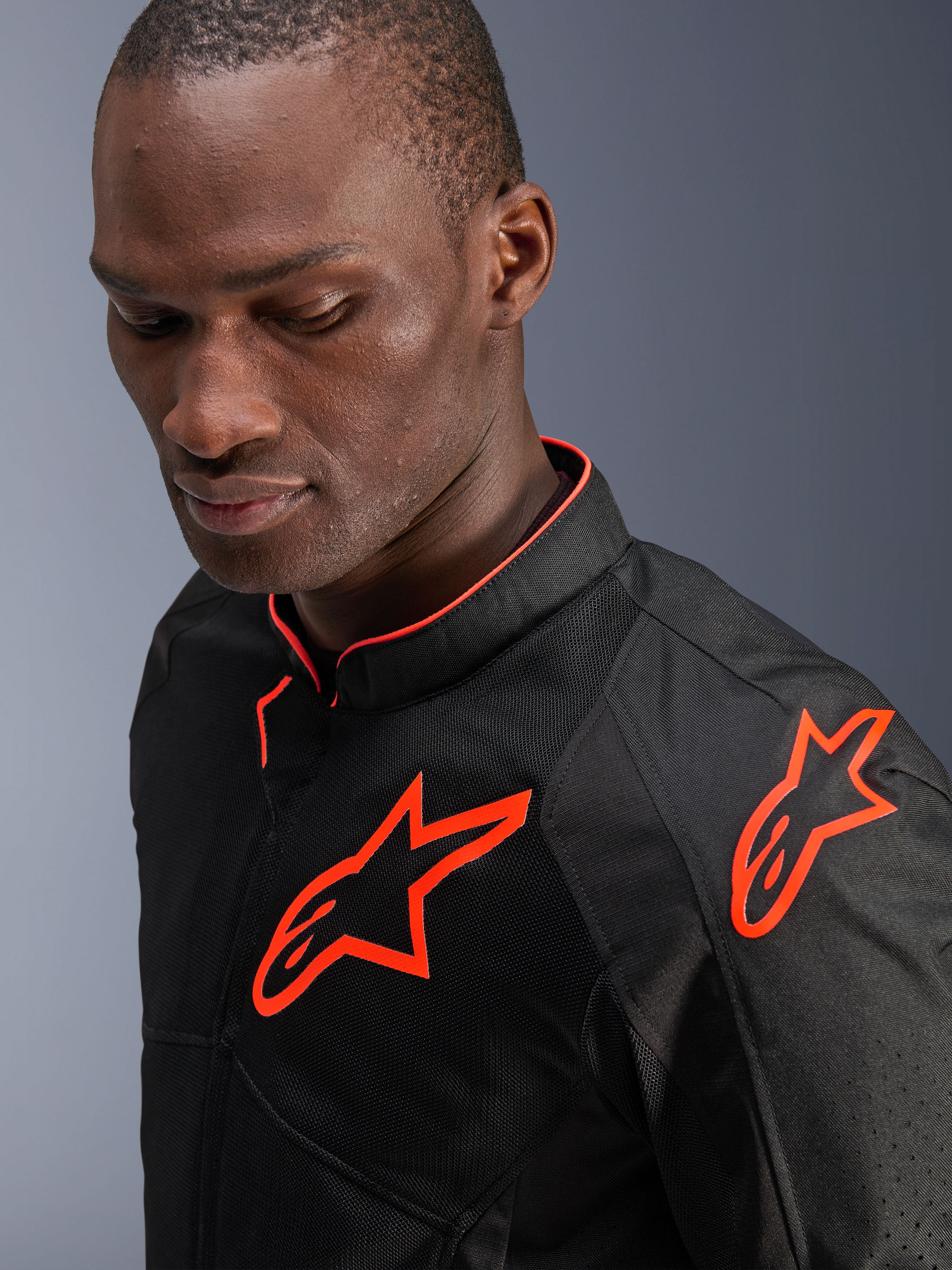 Kurtka Alpinestars Viper Air V4, czarna z czerwonymi akcentami fluo (Black Red Fluo), prezentowana przez modela, zbliżenie pokazujące tekstylne panele z siatki oraz jaskrawe fluorescencyjne czerwone logo Alpinestars na piersi i ramieniu, sportowa odzież motocyklowa