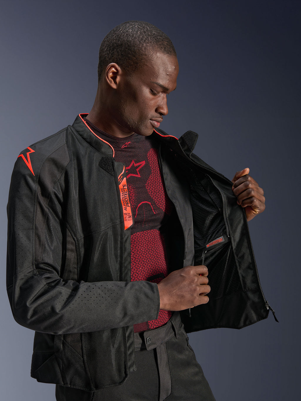 Kurtka Alpinestars Viper Air V4, Black Red Fluo, kurtka motocyklowa z panelami z siatki technicznej, męski model prezentujący wodoodporną wewnętrzną kieszeń i podszewkę, neonowe czerwone akcenty oraz oznaczenie Tech-Air Ready