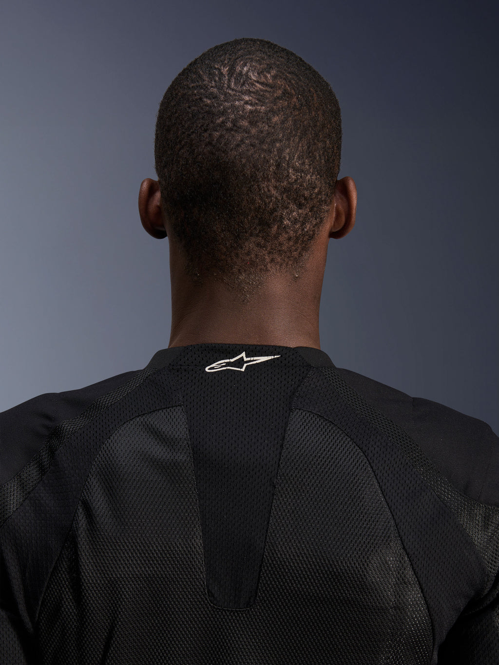 Kurtka Alpinestars Troop-Air, czarna, zbliżenie na kark pokazujące białe logo Alpinestars na oddychającej siatce technicznej, techniczna kurtka motocyklowa zaprojektowana dla maksymalnego przepływu powietrza