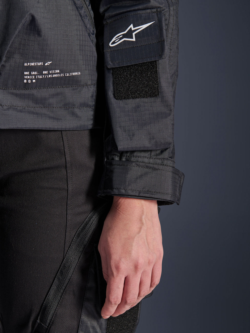 Kurtka Alpinestars Molly Air, zbliżenie na czarny materiał ripstop, białe logo Astar na kieszeni na rękawie z rzepem, regulowany mankiet i nadrukowany tekst brandingowy z boku, miejska damska odzież motocyklowa