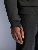 Alpinestars Chrome V2 Sport Hoodie, czarny polar techniczny, zbliżenie na prążkowany mankiet rękawa ze zintegrowaną pętlą na kciuk zapewniającą stabilność podczas jazdy, detal miejskiej odzieży motocyklowej