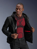 Alpinestars Chrome V2 Sport Hoodie, czarna, męski model w rozpiętej bluzie ukazujący wewnętrzną podszewkę, czerwoną wodoodporną kieszeń i wewnętrzne logo marki, nałożona na czerwono-czarną warstwę bazową, miejska odzież motocyklowa