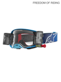 Alpinestars Supertech Firma, gogle motocyklowe do motocrossu i off-roadu, niebieskie i srebrne, wyposażone w zintegrowany system roll-off zapewniający wyraźną widoczność, soczewka z poliwęglanu o wysokiej przejrzystości, szeroki niebieski pasek z białym logo.