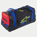 Alpinestars Komodo Travel Bag, torba podróżna na kółkach na sprzęt, czarna z niebieskimi, czerwonymi i jaskrawożółtymi akcentami, niebieskie uchwyty z taśmy, czerwony panel boczny i jaskrawożółte logo, wytrzymała konstrukcja z kółkami do transportu sprzętu motocrossowego i wyścigowego