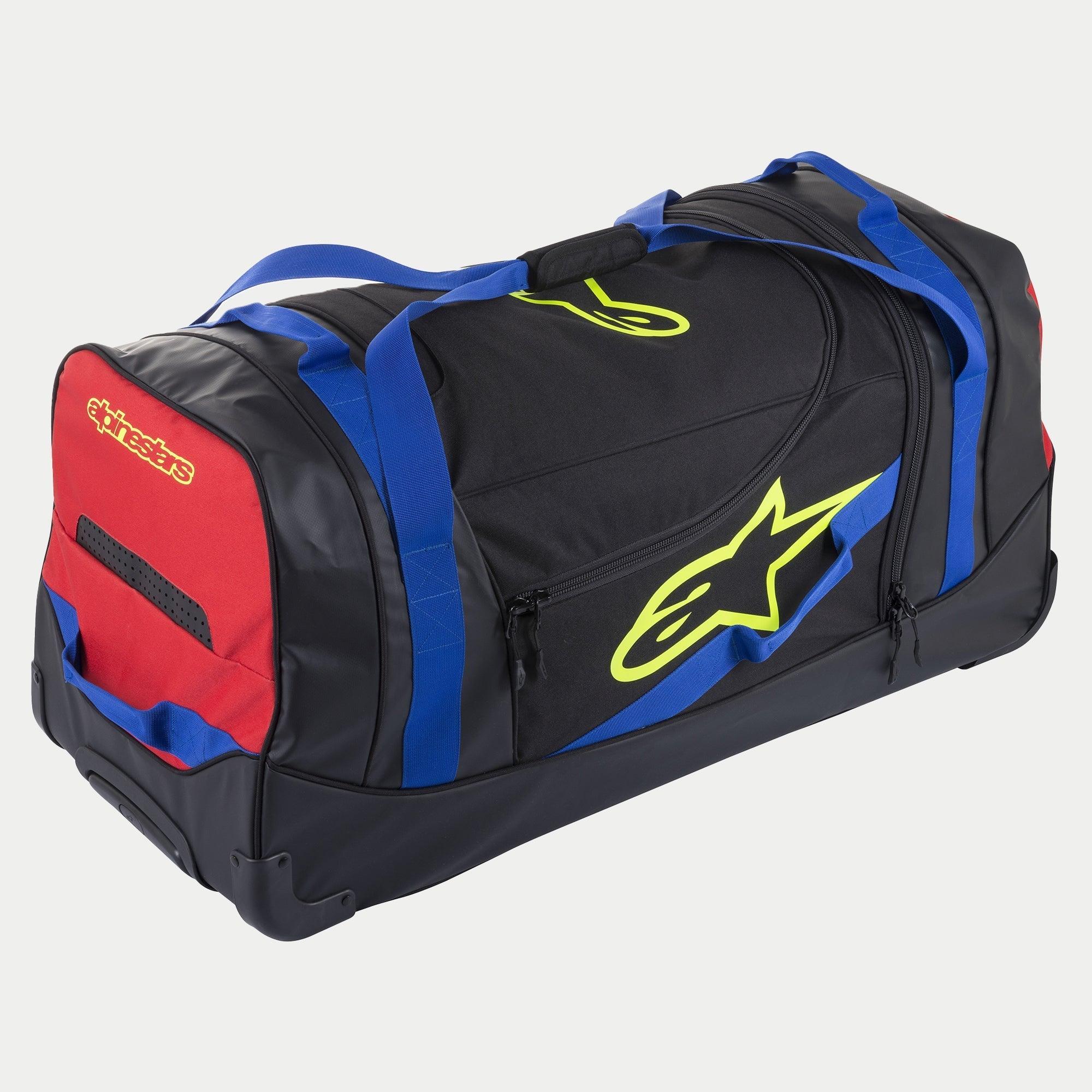 Alpinestars Komodo Travel Bag, torba podróżna na kółkach na sprzęt, czarna z niebieskimi, czerwonymi i jaskrawożółtymi akcentami, niebieskie uchwyty z taśmy, czerwony panel boczny i jaskrawożółte logo, wytrzymała konstrukcja z kółkami do transportu sprzętu motocrossowego i wyścigowego