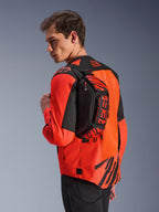 Torba na pas Alpinestars MM93, czarna z jaskrawoczerwonymi (Red Fluo) i jasnoczerwonymi (Bright Red) elementami, noszona przez modela na plecach na czerwono-czarnej kurtce motocyklowej, z wyraźnym brandingiem MM93 i grafikami Marca Marqueza