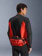 Alpinestars MM93 Waist Bag, motocyklowa torba na pas, jaskrawoczerwona i czarna, noszona na dopasowanej czarno-czerwonej kurtce motocyklowej, posiada przegrody na suwak oraz branding Marc Marquez MM93, wytrzymała konstrukcja tekstylna do jazdy na motocyklu
