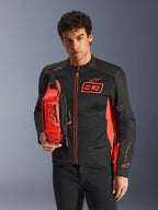 Mężczyzna noszący torbę na pas Alpinestars MM93, w kolorze Red Fluo i czarnym, stylizowaną na torbę na ramię na dopasowanej czarno-czerwonej kurtce motocyklowej, z logo Marc Marquez 93, sportowy design wyścigowy