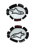 Alpinestars GP Tech Knee Sliders, motocyklowe ochraniacze kolan, biało-czarne, zestaw lewego i prawego slidera z białymi plastikowymi skorupami i czarnym logo Astar, mocowanie na rzep z napisem „ONE GOAL ONE VISION”, profesjonalny sprzęt wyścigowy