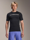 Alpinestars A-Aria Switch Jersey, koszulka rowerowa MTB z krótkim rękawem, czarna z białym napisem Alpinestars na piersi, prezentowana przez modela w fioletowych szortach, lekki materiał techniczny do jazdy po szlakach