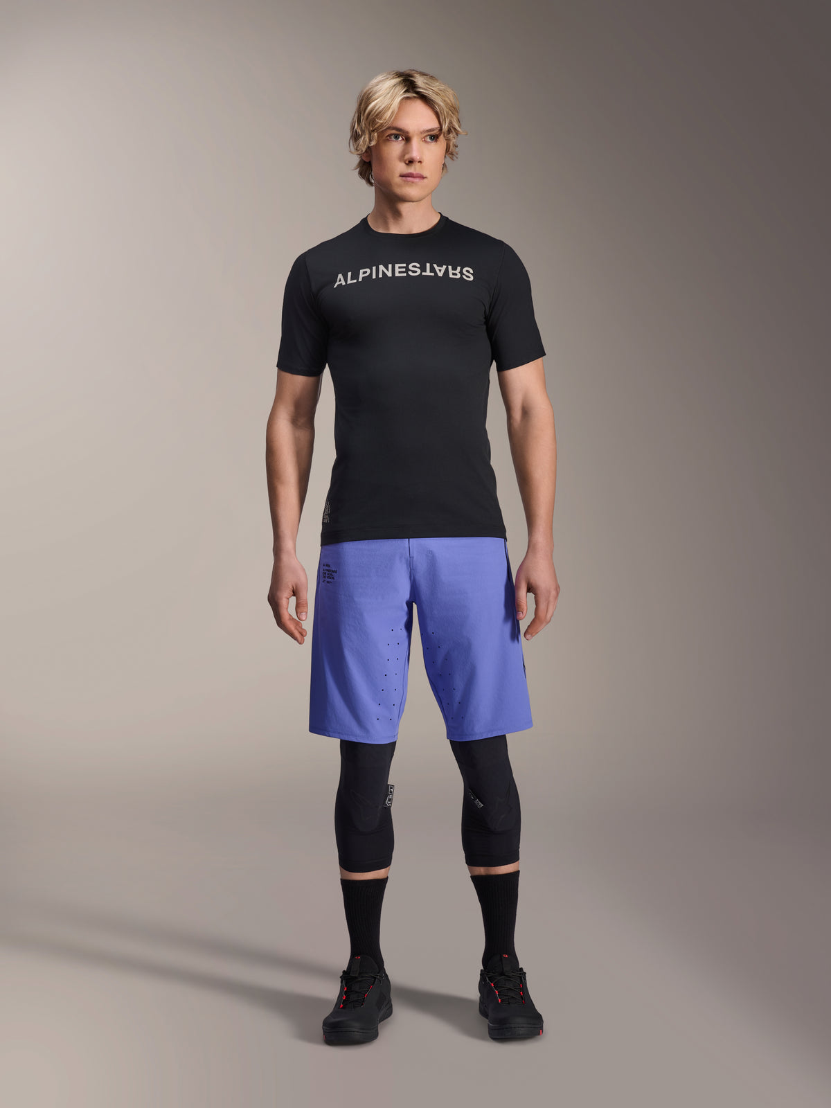 Alpinestars A-Aria Lite Short w kolorze Baja Blue, męskie szorty MTB, noszone z czarną koszulką z krótkim rękawem i ochraniaczami na kolana, laserowe perforacje zapewniające wentylację, sportowa odzież do jazdy na rowerze górskim