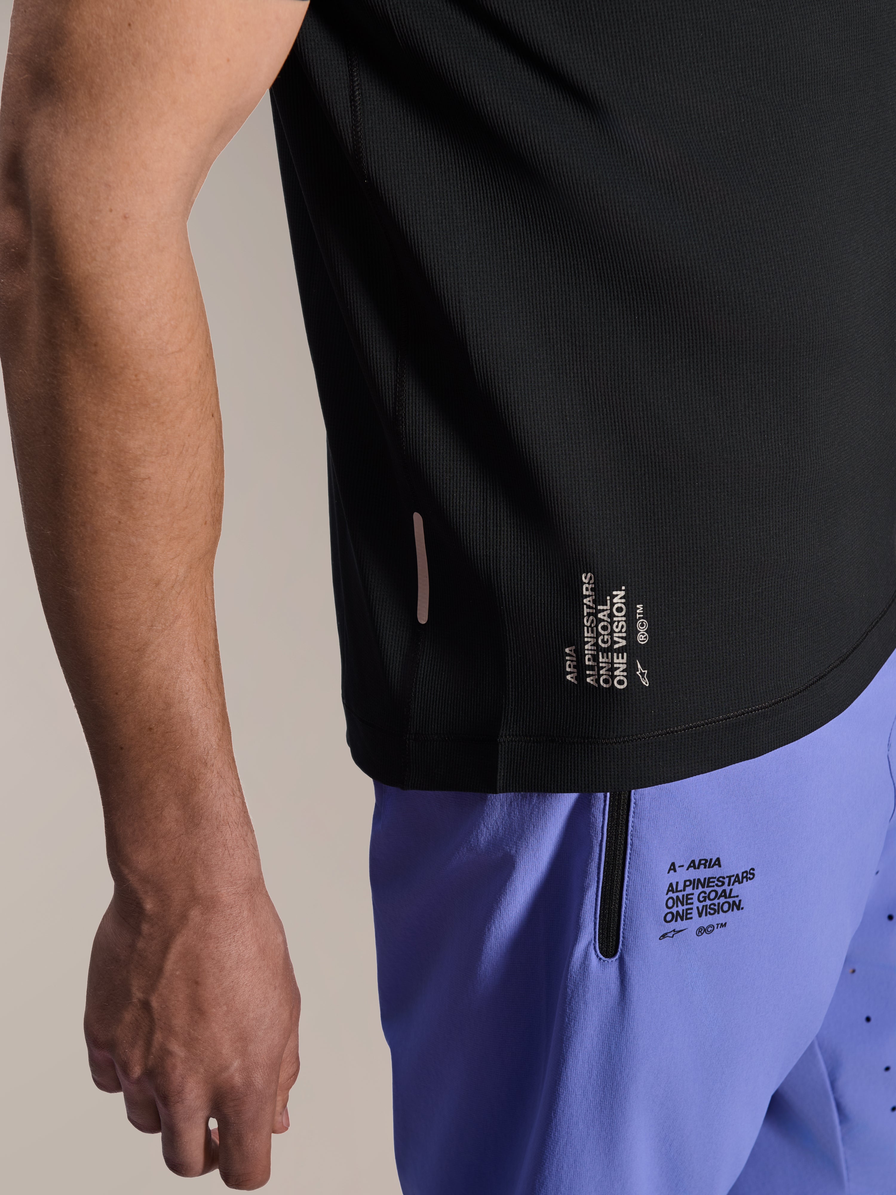 Alpinestars A-Aria Lite Short in Baja Blue, MTB Shorts, featuring screen-printed 'One Goal. One Vision.' branding and zippered pocket, paired with a black A-Aria Switch jersey, close-up view of technical cycling gear.
