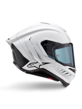 Alpinestars Supertech R10 Solid Helmet, wyścigowy kask motocyklowy, biały połysk i czarny mat, profil boczny, aerodynamiczny design z tylnymi skrzydełkami i bocznymi wlotami powietrza, niebieski przyciemniany wizjer, czarne logo gwiazdy Alpinestars na boku