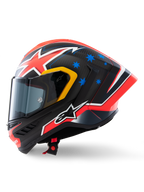 Kask Alpinestars Supertech R10 Miller Limited Edition, widok z boku, matowe wykończenie Carbon Red z widocznym splotem włókna węglowego, czerwono-biała grafika błyskawic, niebieskie gwiazdy z tyłu, żółte akcenty wokół wizjera i białe logo Alpinestars, wyczynowy wyścigowy kask motocyklowy