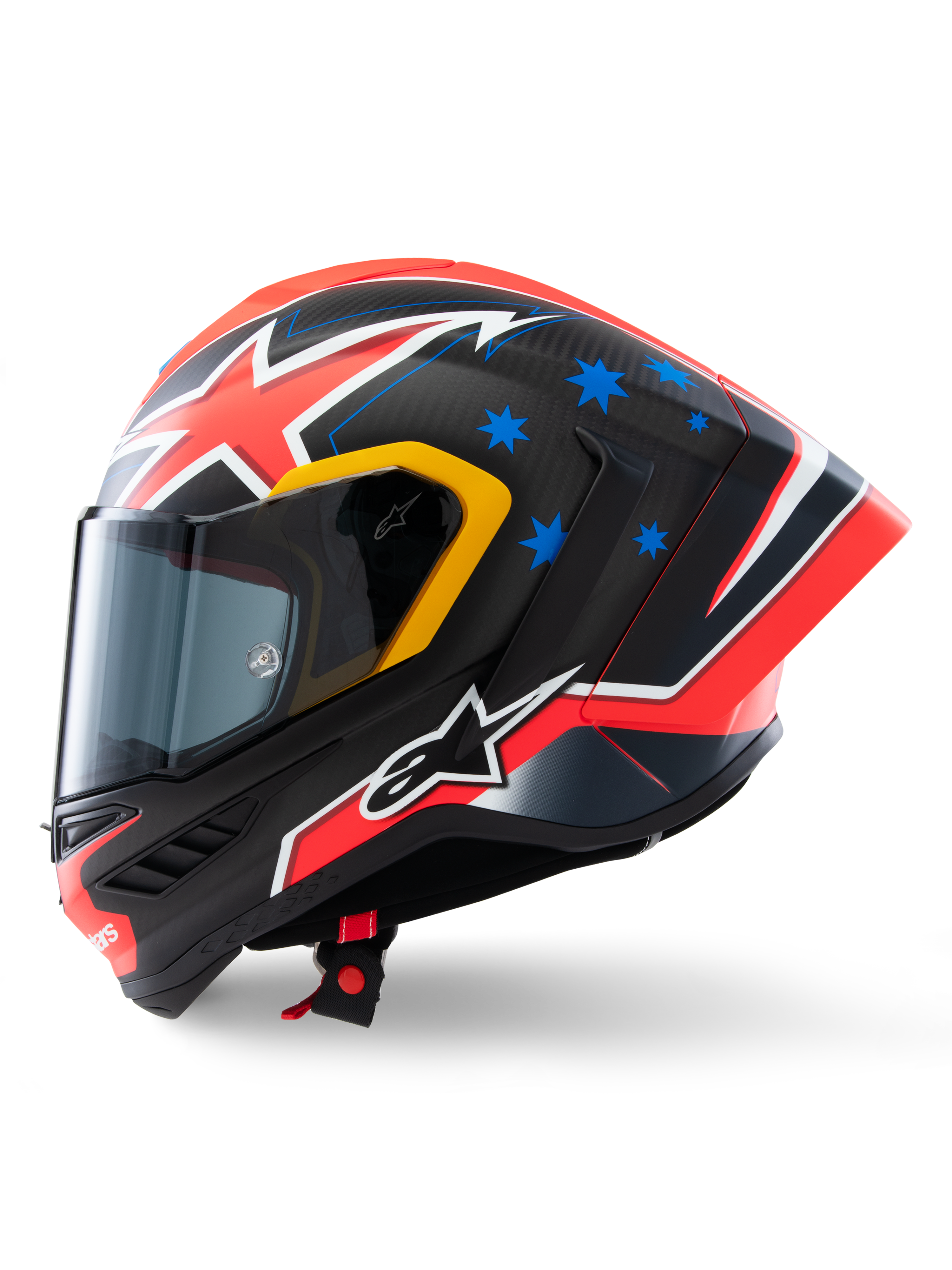 Kask Alpinestars Supertech R10 Miller Limited Edition, widok z boku, matowe wykończenie Carbon Red z widocznym splotem włókna węglowego, czerwono-biała grafika błyskawic, niebieskie gwiazdy z tyłu, żółte akcenty wokół wizjera i białe logo Alpinestars, wyczynowy wyścigowy kask motocyklowy