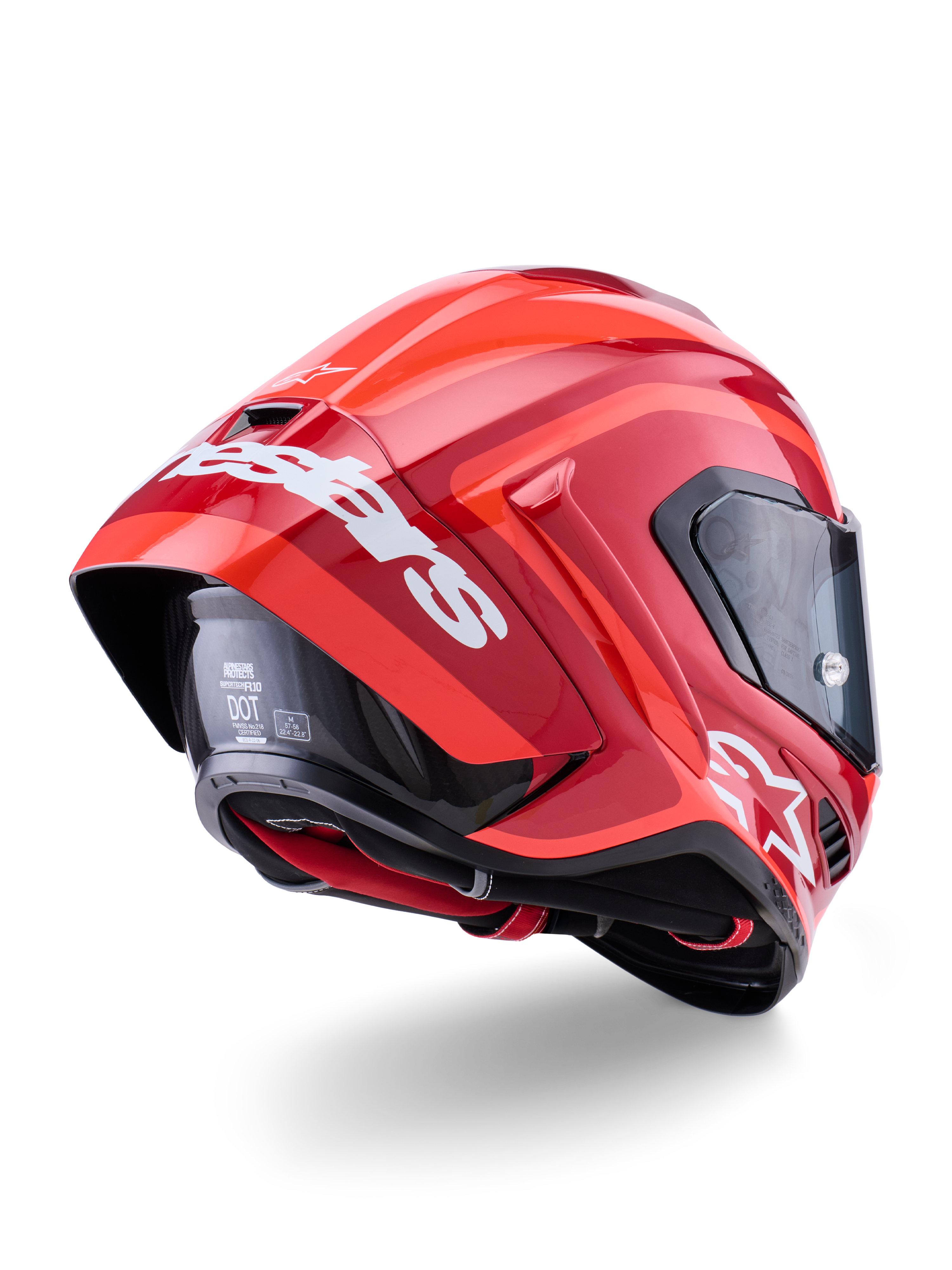 Kask Alpinestars Supertech R10 Arius, czerwony połysk z białymi oznaczeniami marki, widok z tyłu pod kątem trzech czwartych ukazujący aerodynamiczny spoiler, konstrukcja skorupy z włókna węglowego, smukły wyścigowy profil z ciemnym wizjerem