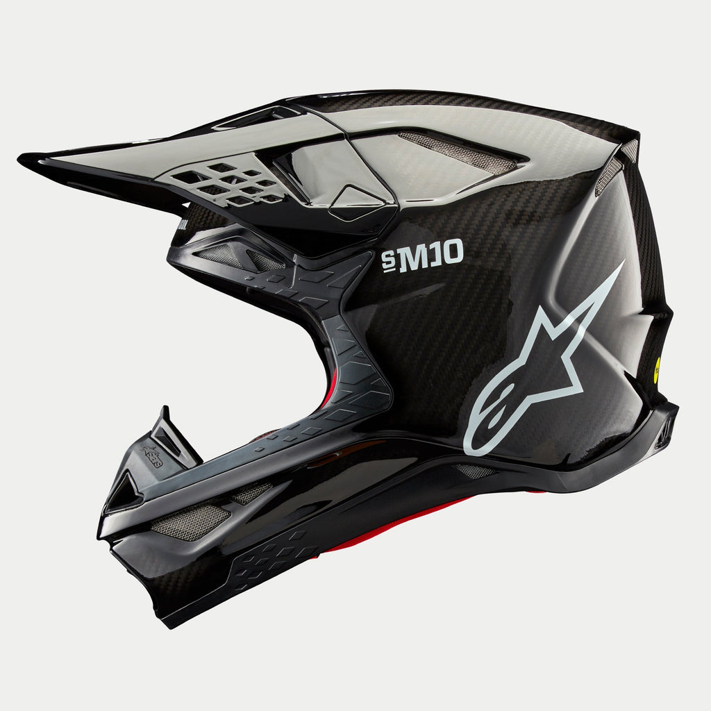 Kask Alpinestars Supertech M10 Solid, kask motocrossowy, czarny błyszczący karbon, profil boczny z widocznym splotem włókna węglowego, białe logo SM10 i Alpinestars, opływowy aerodynamiczny design z otworami wentylacyjnymi osłoniętymi siatką