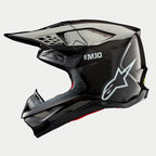 Kask Alpinestars Supertech M10 Solid, kask motocrossowy, czarny błyszczący karbon, profil boczny z widocznym splotem włókna węglowego, białe logo SM10 i Alpinestars, opływowy aerodynamiczny design z otworami wentylacyjnymi osłoniętymi siatką