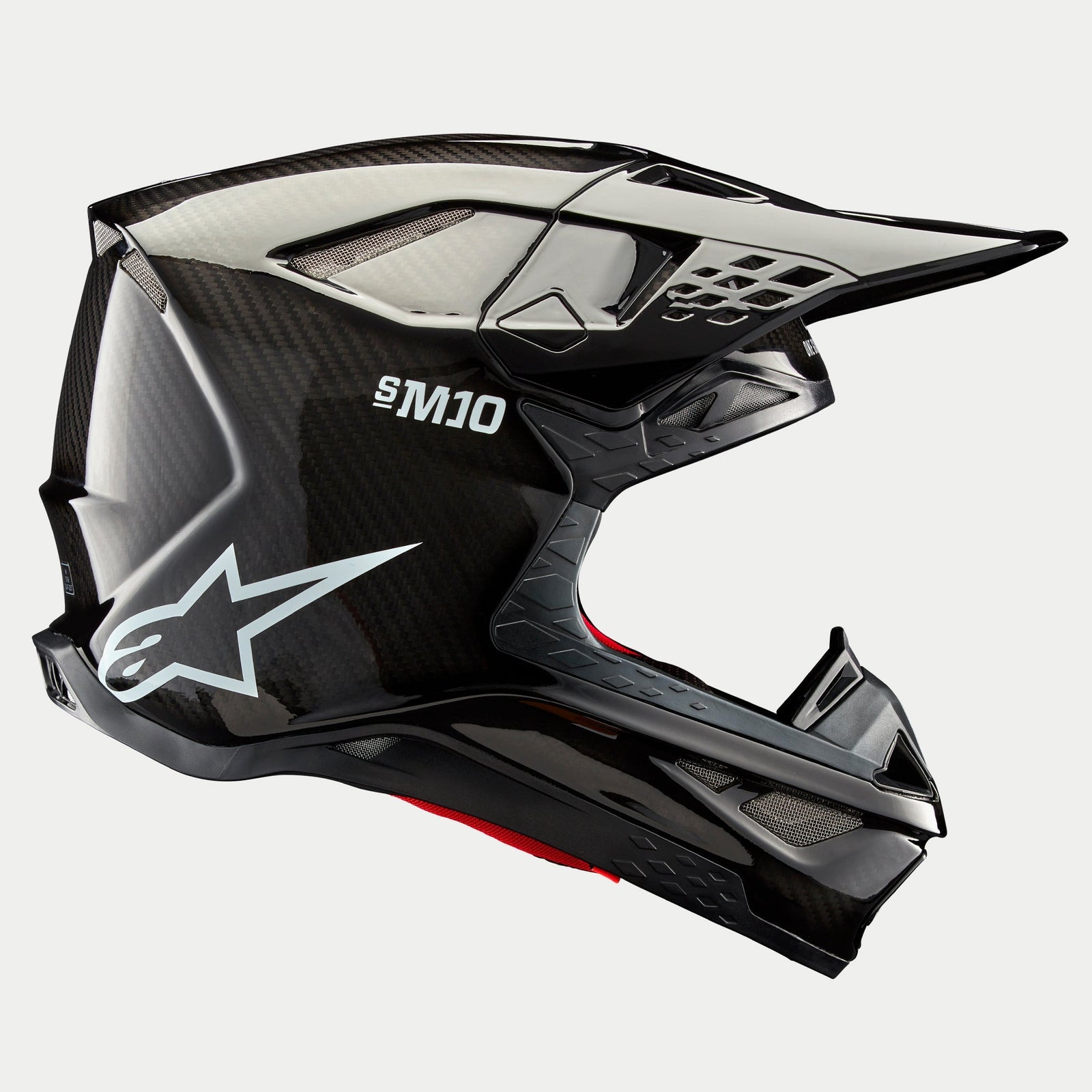 Kask Alpinestars Supertech M10 Solid, Black Glossy Carbon, kask motocrossowy, widok z profilu prezentujący splot błyszczącego włókna węglowego, oznaczenie S-M10, białe logo gwiazdy Alpinestars, aerodynamiczny design z daszkiem i otworami wentylacyjnymi