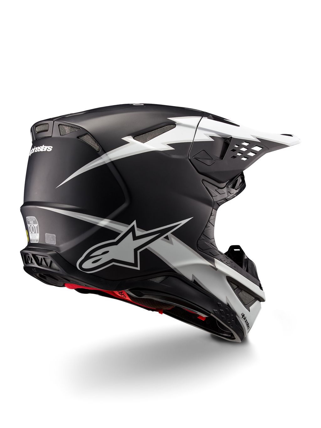 Kask Alpinestars Supertech M10 Ampress, kask motocrossowy, czarno-biały mat, z wyrazistą grafiką białych błyskawic na czarnej matowej skorupie, widok z tyłu pod kątem trzech czwartych pokazujący branding Alpinestars i otwory wentylacyjne