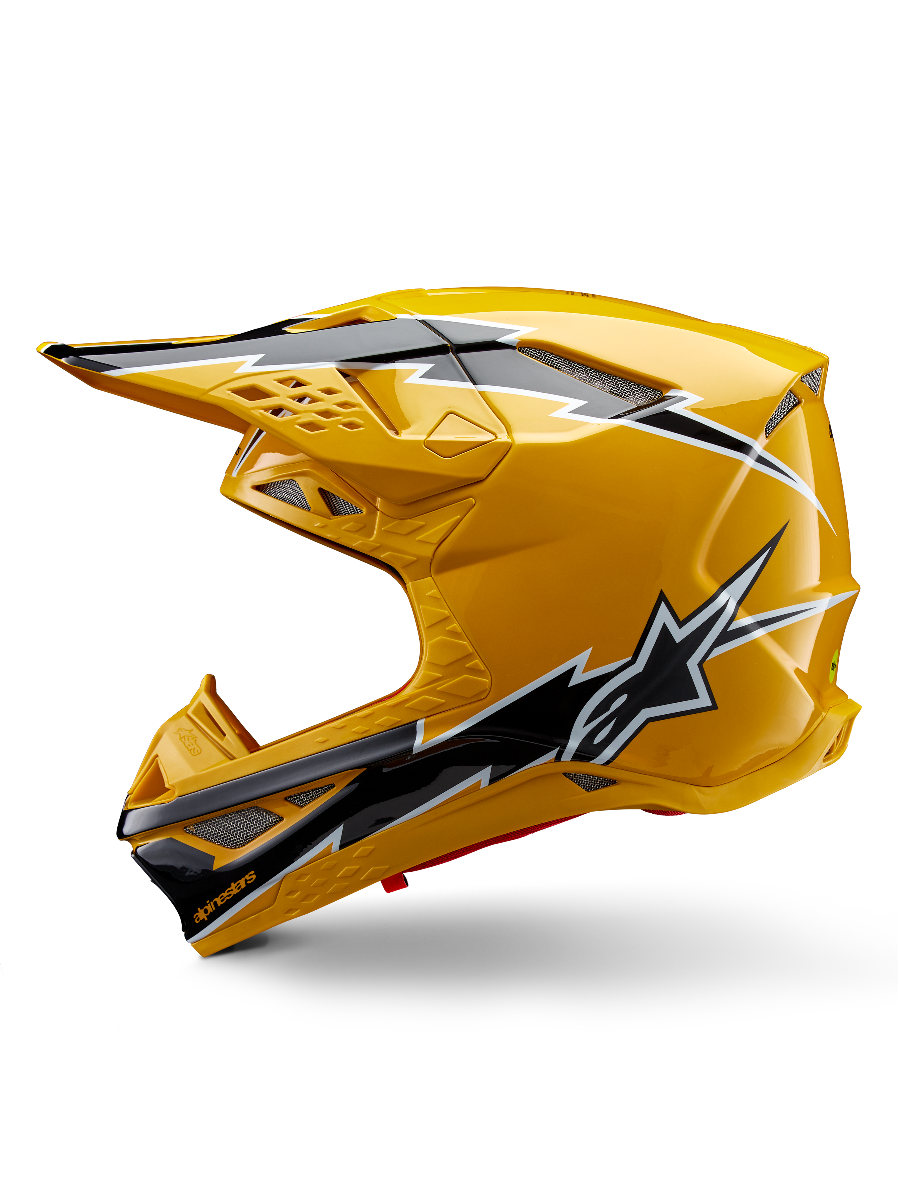 Kask Alpinestars Supertech M10 Ampress, kask motocrossowy, błyszczący żółty z czarno-białą grafiką, widok z boku z kanciastymi wzorami, logo gwiazdy Alpinestars, liczne otwory wentylacyjne ze srebrną siatką, profesjonalny sprzęt do wyścigów terenowych