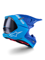 Kask Alpinestars Supertech M10 Flood, kask motocrossowy, jasnoniebieski i granatowy z widocznym czarnym włóknem węglowym, profil tylno-boczny pokazujący otwory wentylacyjne i białe logo, czerwona wyściółka, zaawansowana konstrukcja aerodynamiczna do jazdy w terenie