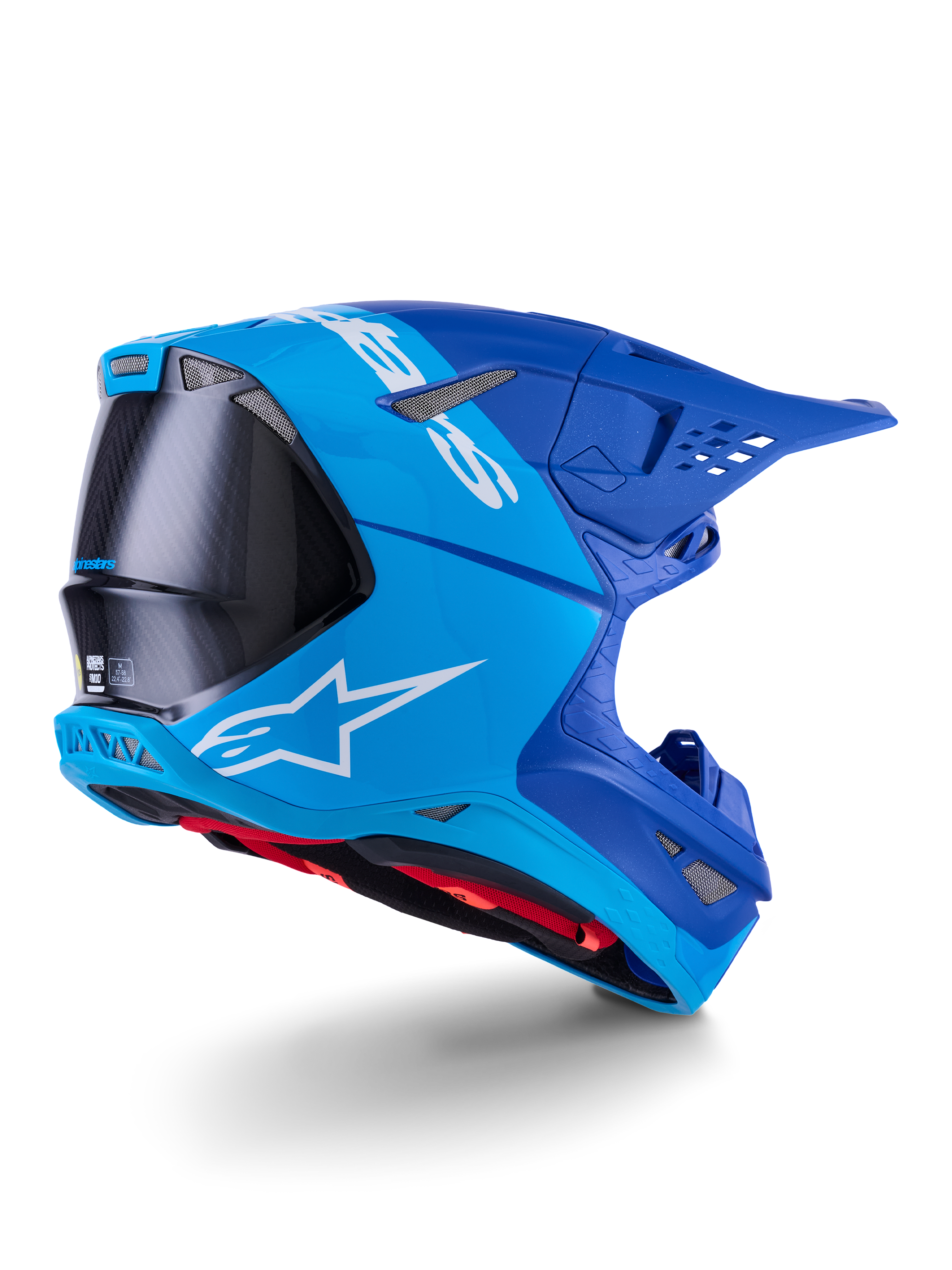 Kask Alpinestars Supertech M10 Flood, kask motocrossowy, jasnoniebieski i granatowy z widocznym czarnym włóknem węglowym, profil tylno-boczny pokazujący otwory wentylacyjne i białe logo, czerwona wyściółka, zaawansowana konstrukcja aerodynamiczna do jazdy w terenie