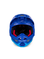 Kask Alpinestars Supertech M10 Flood ECE, kask motocrossowy, metaliczny i średni niebieski z czarnymi karbonowymi akcentami, widok z przodu ukazujący szczękę i otwór na gogle, białe logo i napisy Alpinestars, czerwona wyściółka wewnętrzna, profesjonalna ochrona off-road