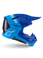 Kask Alpinestars Supertech M10 Flood, kask motocrossowy, metaliczny i średni niebieski z czarnymi karbonowymi akcentami, widok z boku, białe logo, aerodynamiczny design z otworami wentylacyjnymi, detale o strukturze włókna węglowego, profesjonalna ochrona do wyścigów off-road